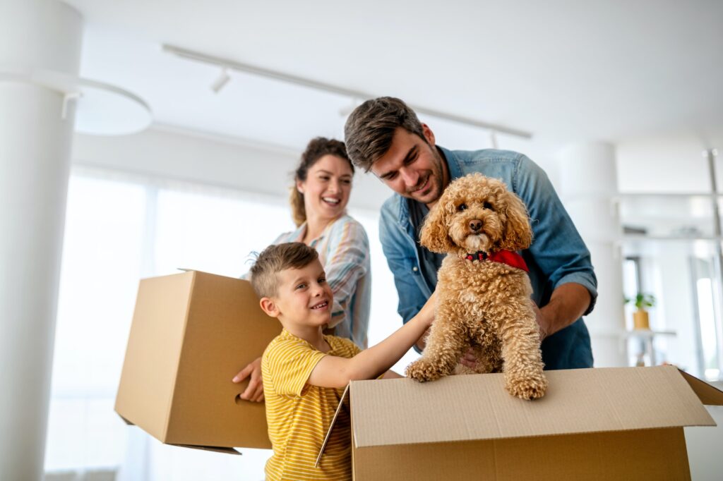 Happy family with children moving with boxes in a new apartment house